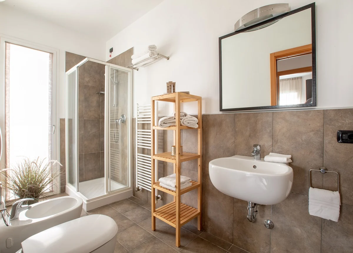 Bagno con doccia, lavabo e mensole in legno