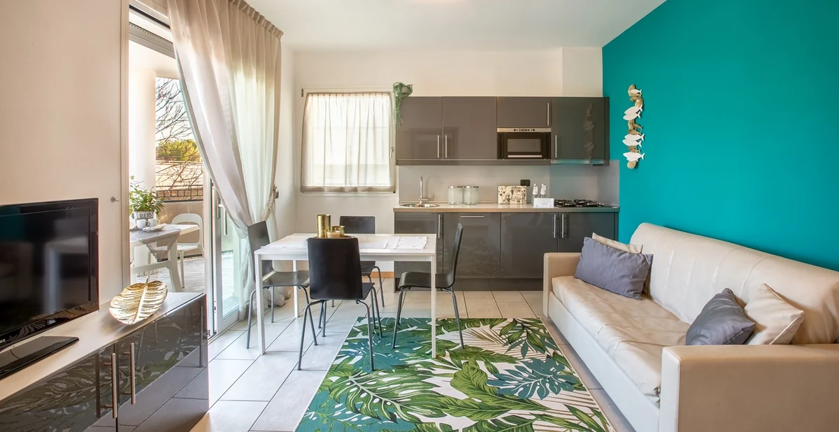 Zona giorno con divano, TV e cucina a vista